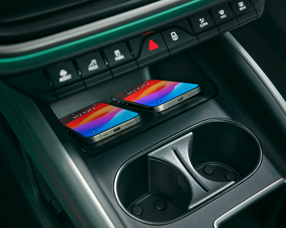 two phones sit side by side in a storage compartment next to two cup holders